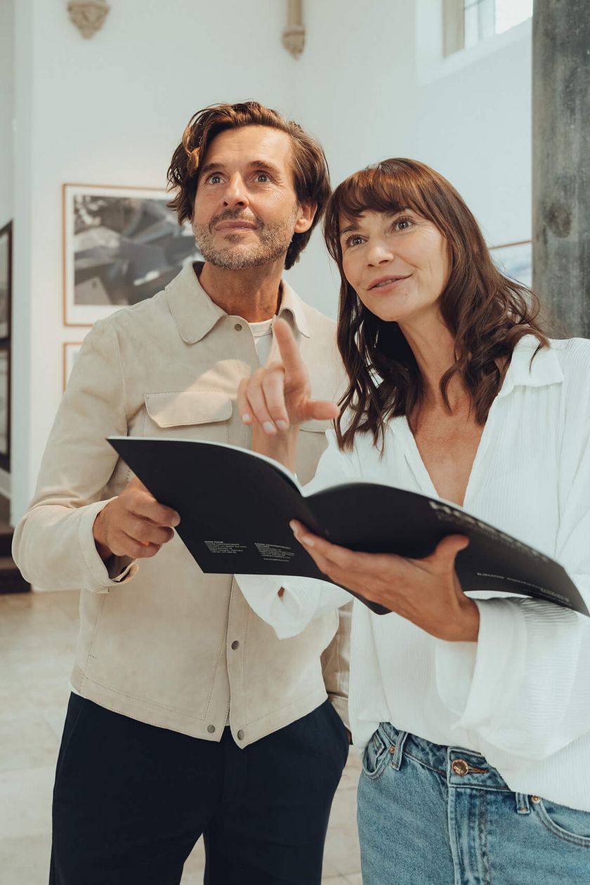 Two people are holding a brochure and looking interested.