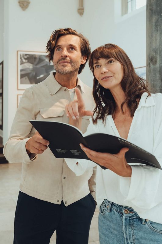 Two people are holding a brochure and looking interested.