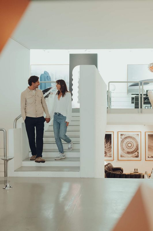 Two people walk through a bright exhibition room.