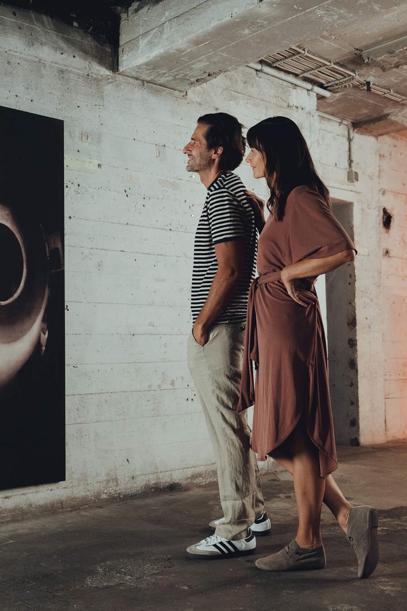Two people are looking at a painting on the wall in a vault.