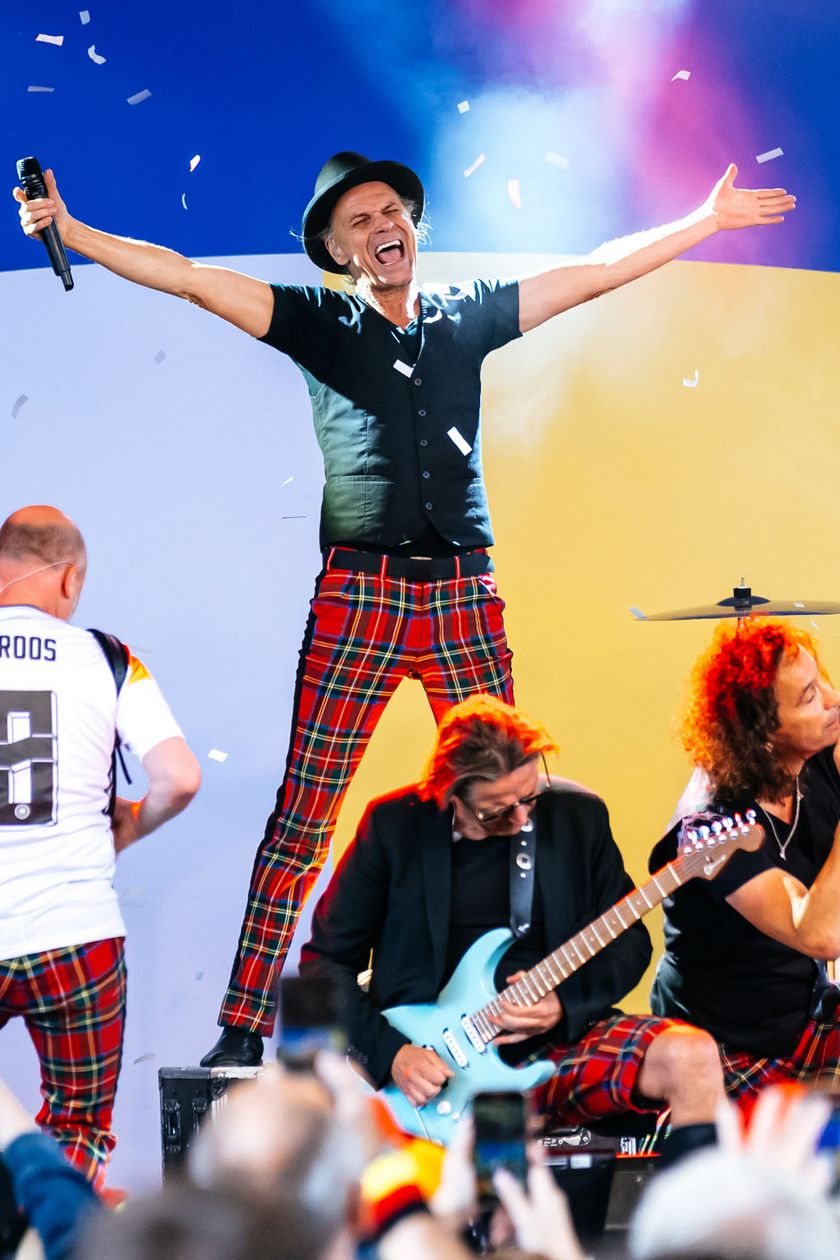 A Kölsch band performs on stage. The singer stretches out his arms and appears euphoric.