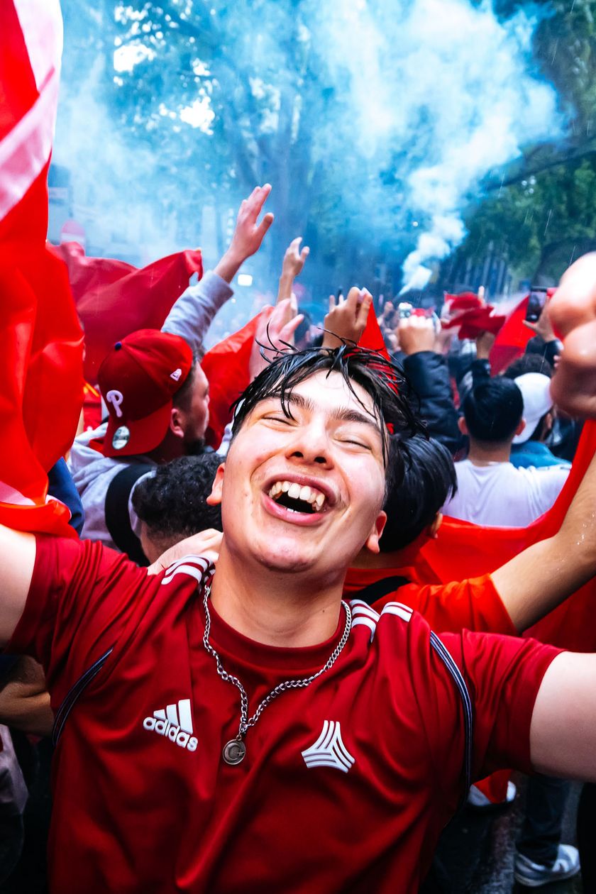 A young fan in a red jersey is delighted and cheering. Around him are many fans.