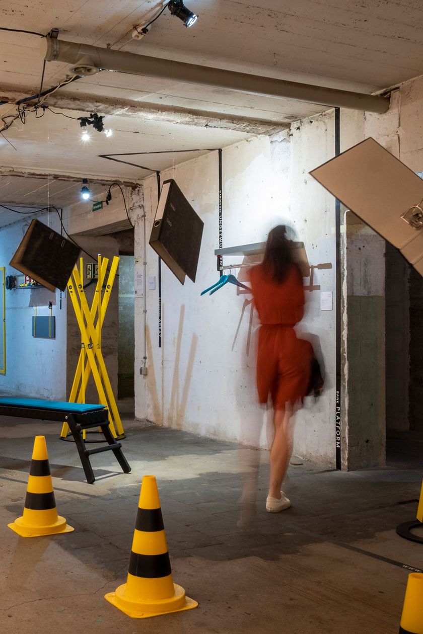 An underground industrial space with concrete walls. Abstract art installations are distributed throughout the space.