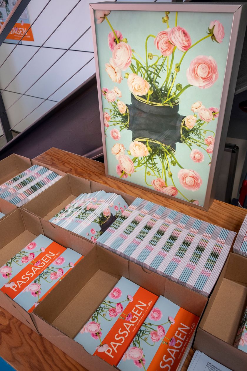 A box of brochures about the passages is sitting on a table, behind it a floral painting.