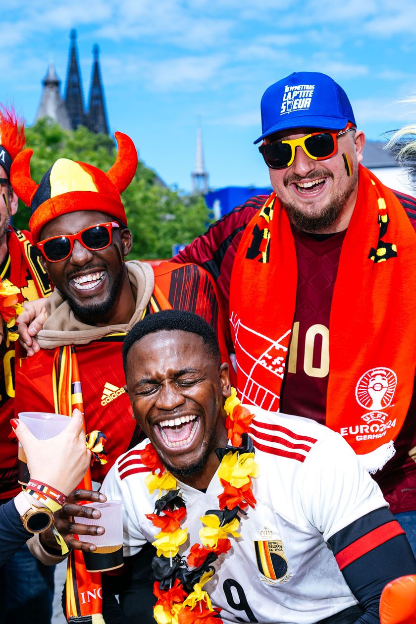 Six people are posing in red jerseys and funny headwear. The mood is exuberant and cheerful.