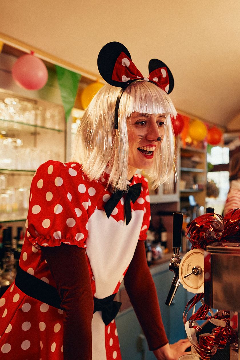 A person dressed as Minnie Mouse looks over the counter and speaks.